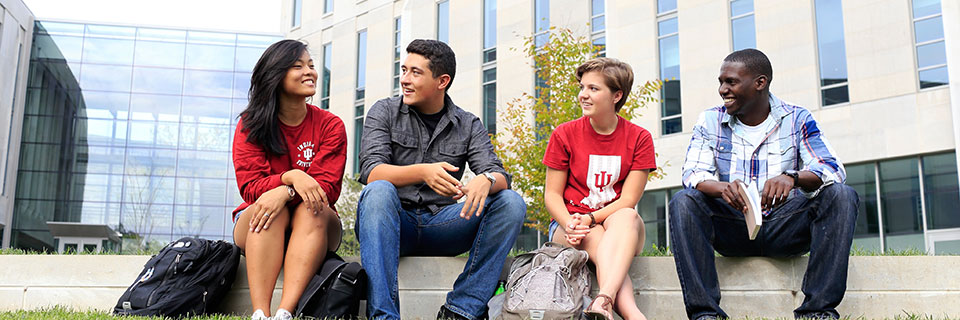 A group of four students meet outside a campus building